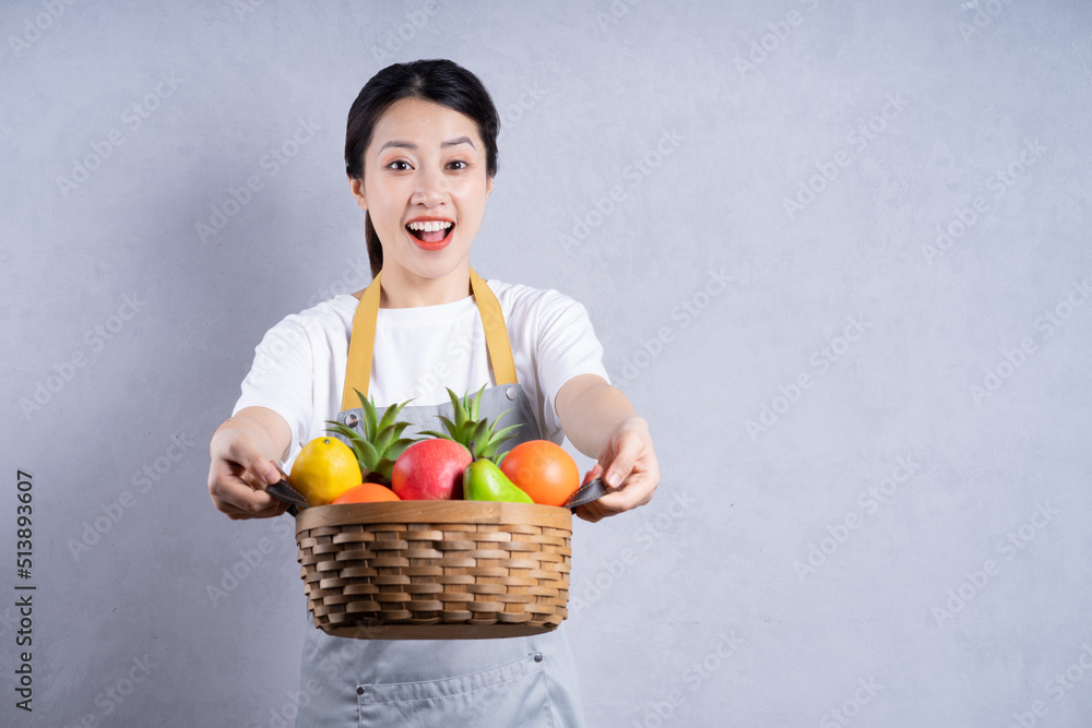 Young Asian woman holding vegetables on background Young Asian woman holding vegetables on background