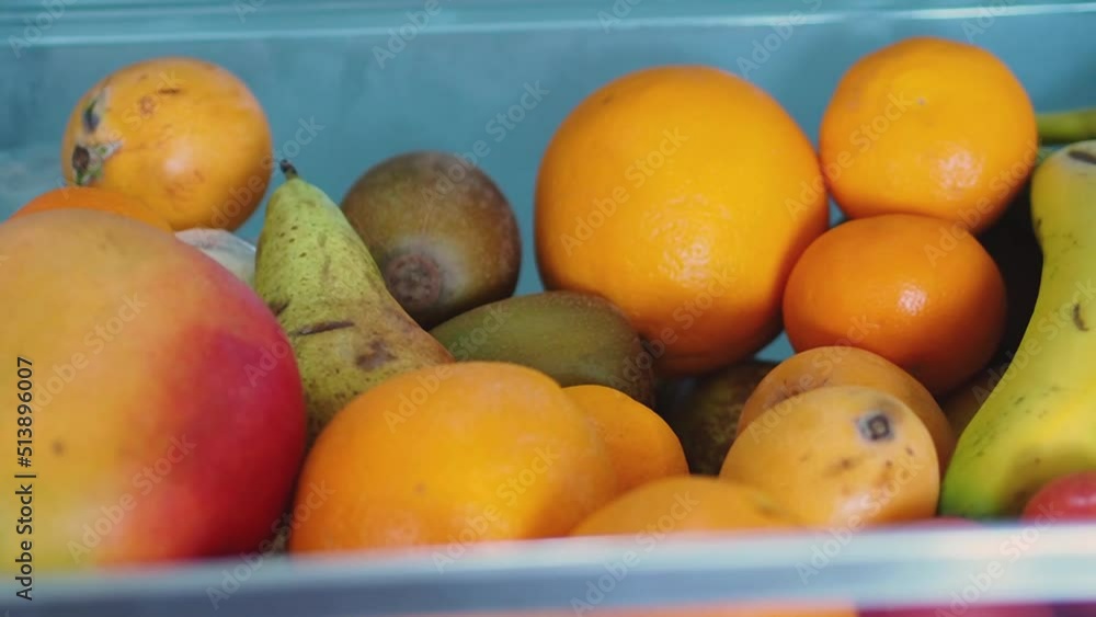 Fridge drawer at home full of fresh, tasty and colorful fruit as mango, clementine, pear, orange, bananas and loquat. Healthy lifestyle eating for a vegetarian diet. Summer fruit in a refrigerator Fridge drawer at home full of fresh, tasty and colorful fruit as mango, clementine, pear, orange, bananas and loquat. Healthy lifestyle eating for a vegetarian diet. Summer fruit in a refrigerator
