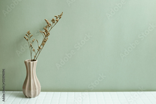 Vase of dry flowers on white table. khaki green wall background photo