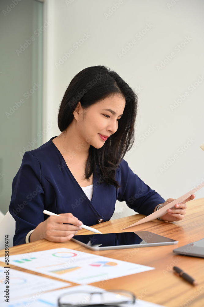 Portrait of female manager holding document and using digital tablet at wooden office Portrait of female manager holding document and using digital tablet at wooden office