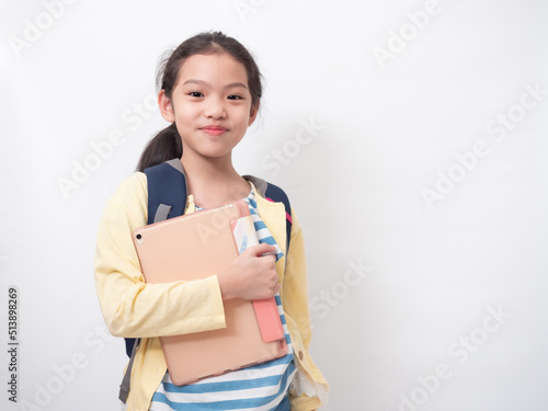 Asian little cute girl 9 year old with backpack and holding a tablet on hands.Primary school lovely kid with happiness. photo