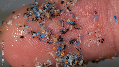 Particles of plastic crushed in water on the ecelogy researcher's finger. Plastic over pollution of the world ocean photo
