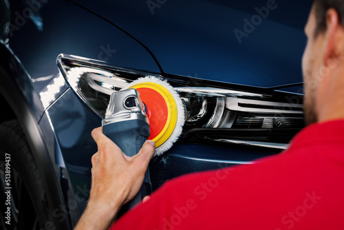 man polishing car headlight with polish machine. restore vehicle lights photo