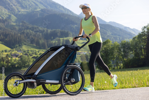 Active family concept. Fit and healthy mother runs on a track while pushing a stroller