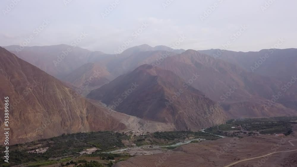 panning aerial drone view between mountains over a village in the highlands of Lunahuana at sunset in 4k panning aerial drone view between mountains over a village in the highlands of Lunahuana at sunset in 4k