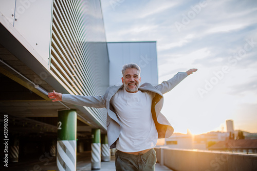 Φωτογραφία Portrait of happy energetic mature businessman with arms outstretched balancing on wall , feeling free, work life balance concept