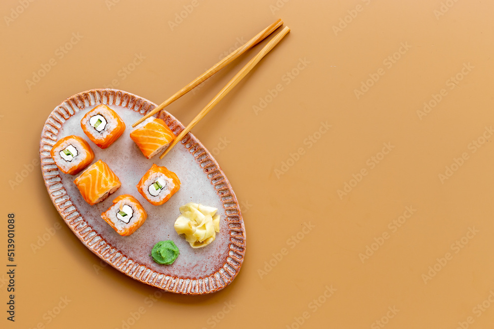 Japanese cuisine. Salmon sushi rolls set on plate, top view Japanese cuisine. Salmon sushi rolls set on plate, top view