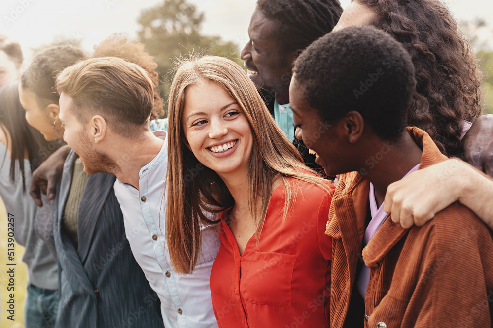 Group of multi-ethnic young people cheering at the park arm on shoulders - diversity and inclusion lifestyle people concept - focus on the blonde girl at center Group of multi-ethnic young people cheering at the park arm on shoulders - diversity and inclusion lifestyle people concept - focus on the blonde girl at center