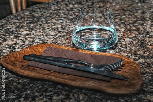 Cutlery and a glass of water on the granite countertop in the restaurant.