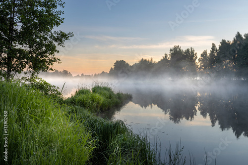 Morning landscape with fog and a pond. Dawn over the lake in the early morning.