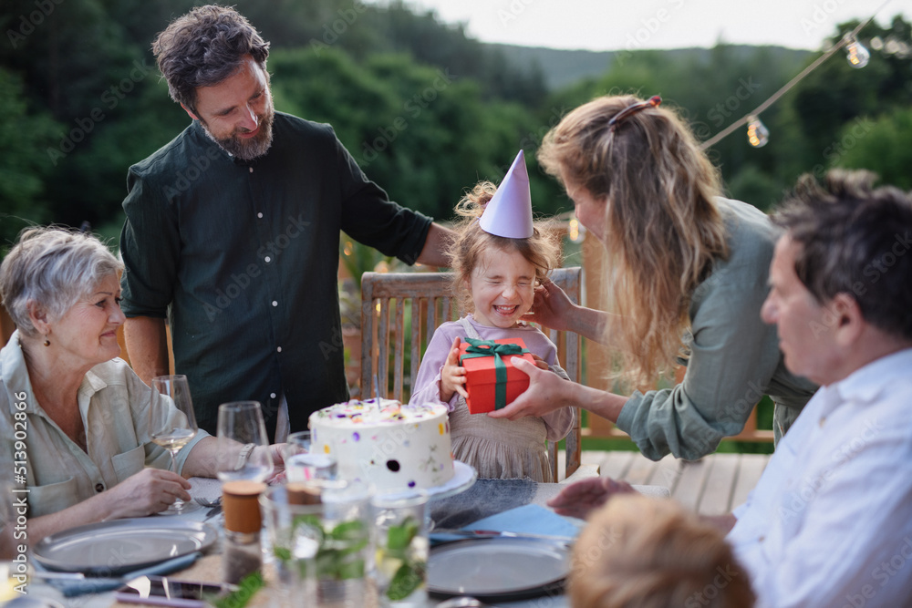 Multi generation family celebrating birthday of little girl and having garden party outside on patio. Multi generation family celebrating birthday of little girl and having garden party outside on patio.