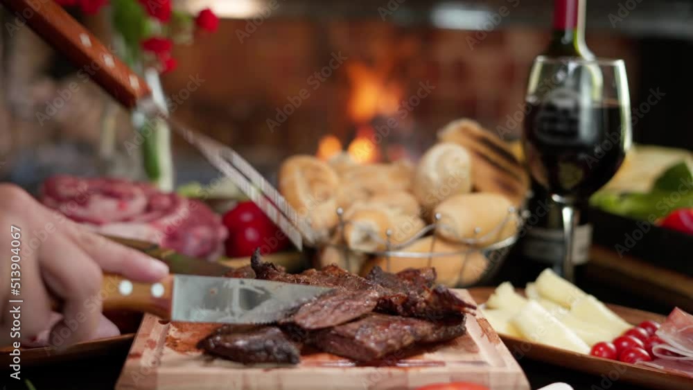 dolly movement towards a table with vegetables,
a glass of wine, bread, raw meat, sausages, with a fire in the background, while a hand with cutlery leaves a cut of roast meat on a wooden board dolly movement towards a table with vegetables,
a glass of wine, bread, raw meat, sausages, with a fire in the background, while a hand with cutlery leaves a cut of roast meat on a wooden board