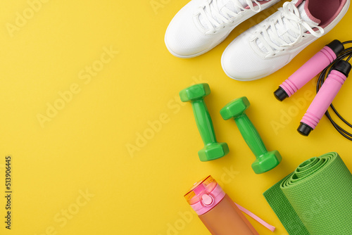 Sports concept. Top view photo of pink skipping rope bottle of water dumbbells green sports mat and white sneakers on isolated yellow background with empty space