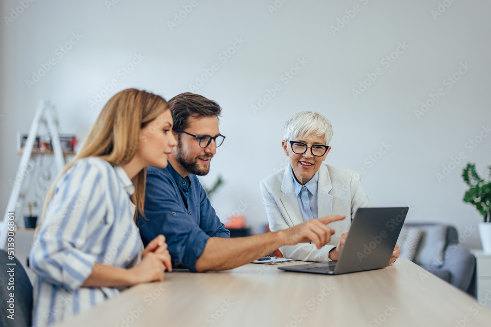 Man showing something to an insurance agent and his wife, over the laptop, choosing the right insurance Man showing something to an insurance agent and his wife, over the laptop, choosing the right insurance