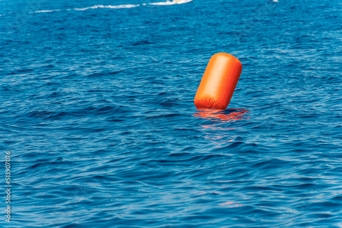 One large orange inflatable signal buoy floating in the blue Mediterranean sea, Gulf of La Spezia, Liguria, Italy, Europe.