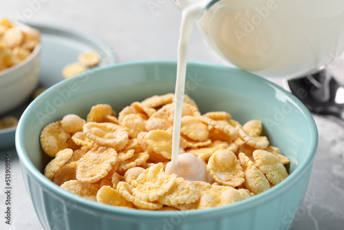 Fototapeta Naklejka Na Ścianę i Meble -  Pouring milk into bowl with cornflakes on table, closeup
