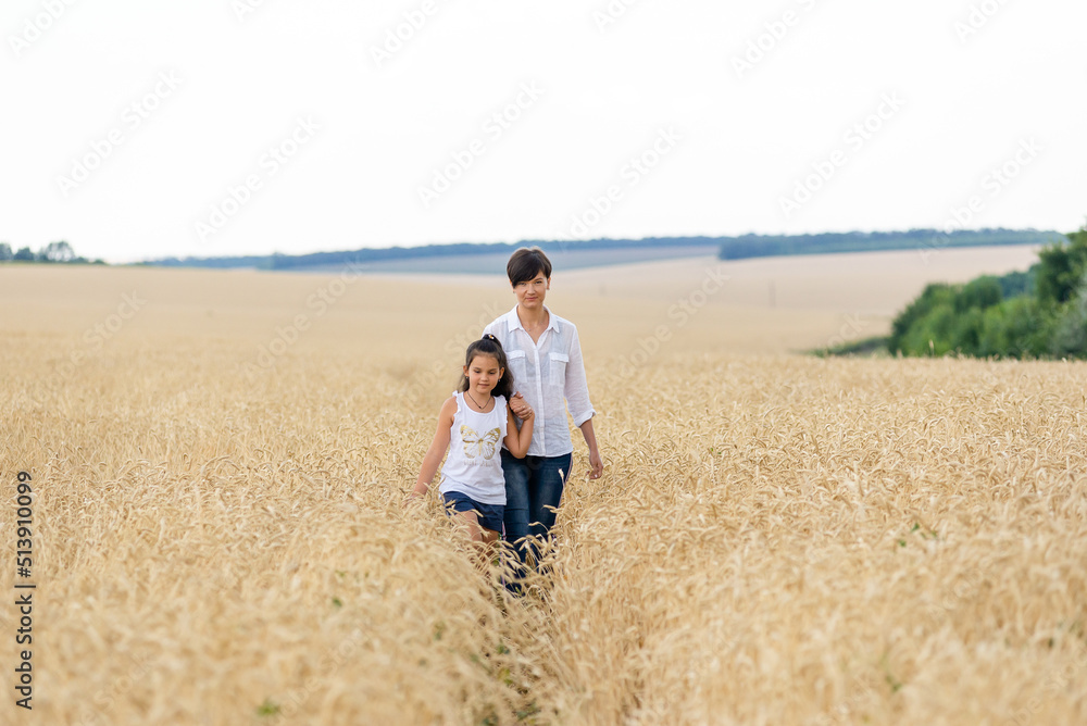 World food crisis. Deficit of grain in the world markets. Mom and daughter are walking in a wheat field. World food crisis. Deficit of grain in the world markets. Mom and daughter are walking in a wheat field.
