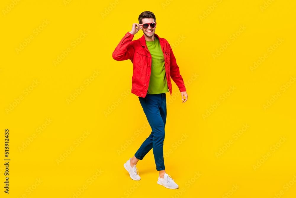 Full length photo of funky brunet millennial guy go wear glasses shirt trousers shoes isolated on yellow background