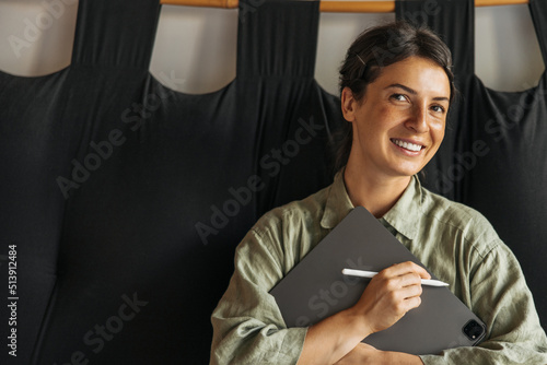 Beautiful young caucasian woman with snow-white smile holds new tablet with stylus. Brunette is wearing khaki shirt. Concept of using devices