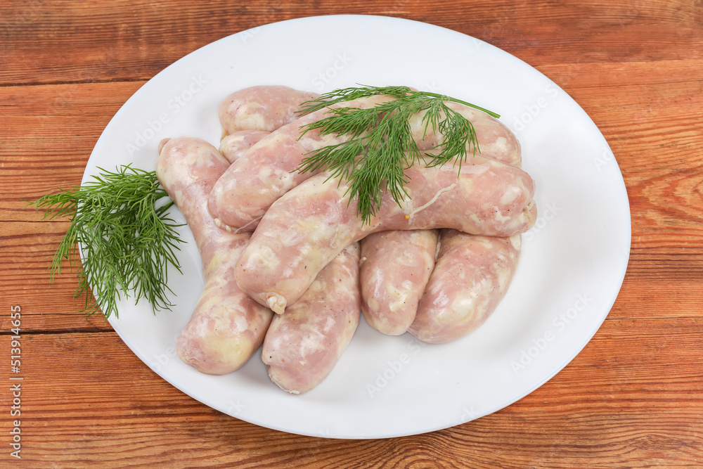 Raw thick chicken sausages on dish on the rustic table Raw thick chicken sausages on dish on the rustic table