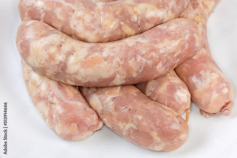 Raw short thick chicken sausages on dish, fragment close-up Raw short thick chicken sausages on dish, fragment close-up