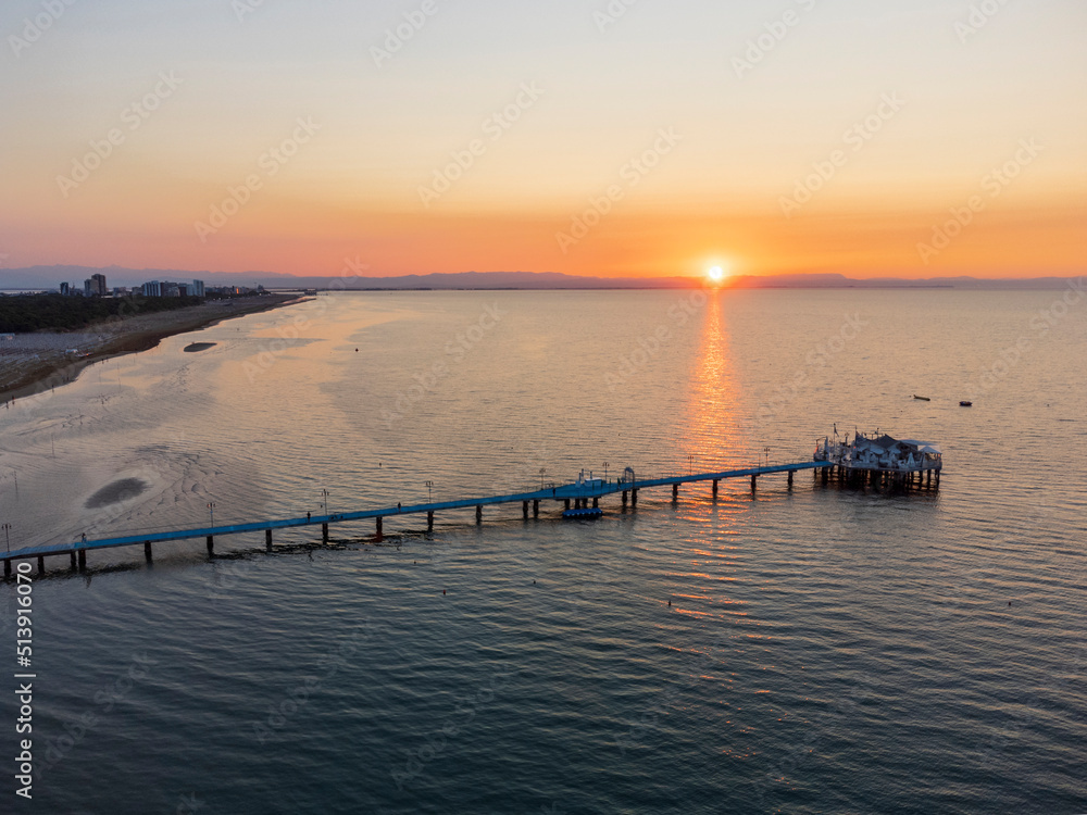 Fototapeta premium Sunrise in Lignano Sabbiadoro seen from above. From the sea to the lagoon, the city of holidays