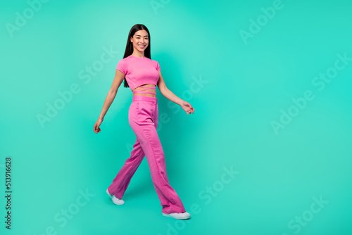 Full body profile side image of cheerful energetic lady in pink outfit go on walk isolated on turquoise color background © deagreez