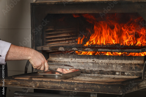 Chef makes beef steak on open fire in restaurant