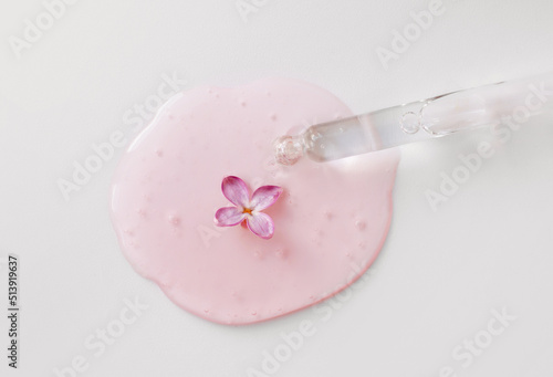 Fototapeta Naklejka Na Ścianę i Meble -  Closeup of pipette with serum, oil, gel with lilac flowers on white background. Skin care, natural beauty products presentation concept. Macro. Romantic floral composition. Front view, high angle shot