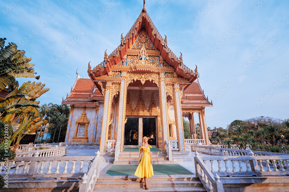 Fototapeta premium Travel by Asia . Young woman in hat and yellow dress walking near the Chalong buddhist temple on Phuket Island in Thailand.