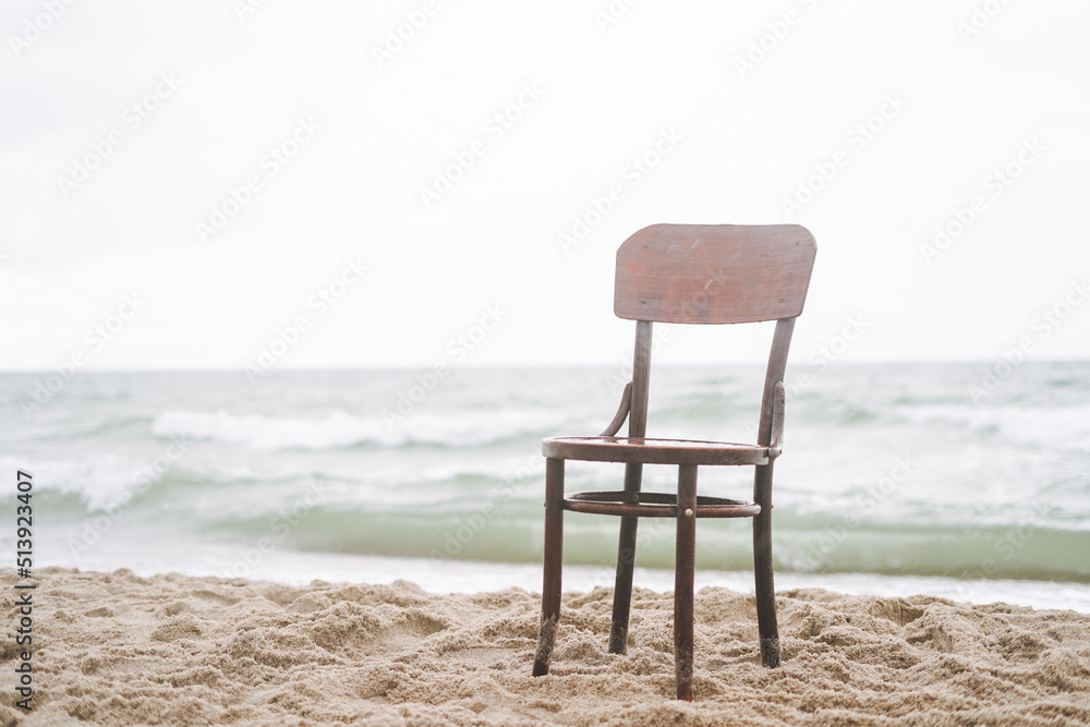 Vintage wooden chair on the sand by the sea in a storm