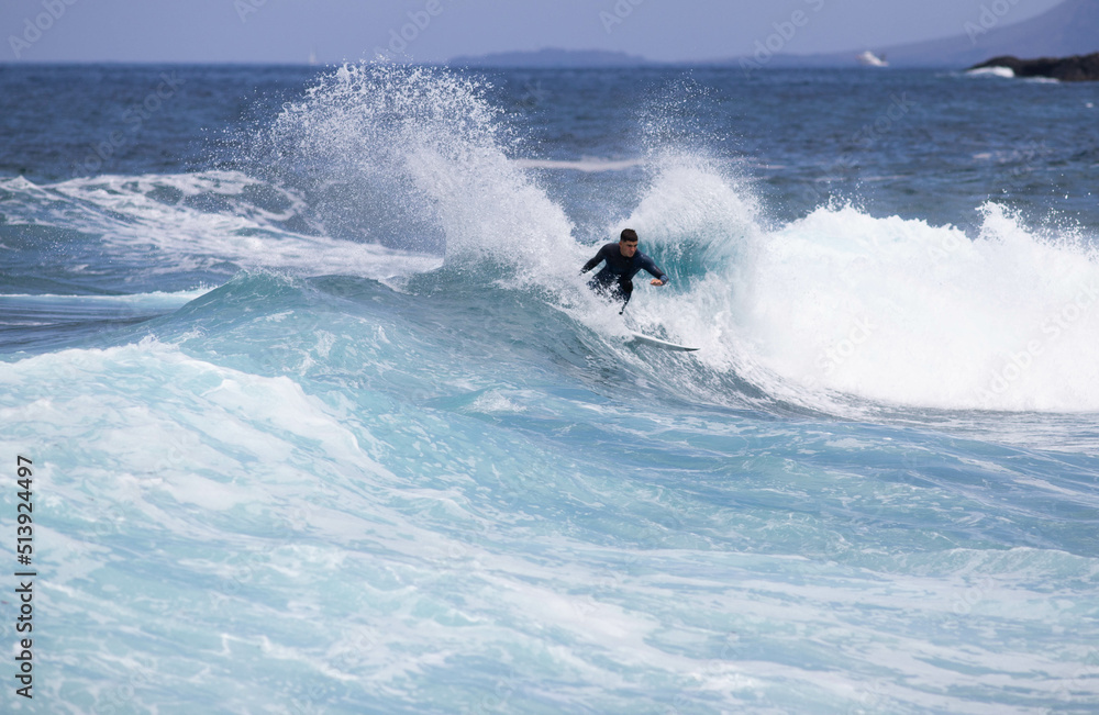 PUERTO DE SANTIAGO, TENERIFE - JUNE 2022: surfer riding the waves in Tenerife PUERTO DE SANTIAGO, TENERIFE - JUNE 2022: surfer riding the waves in Tenerife
