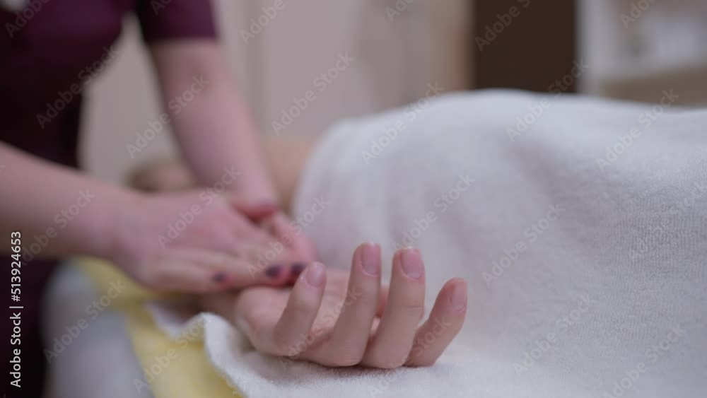 Close-up masseur hand rubbing palm of Caucasian woman in slow motion indoors. Unrecognizable professional expert massaging skin and fingers of client in beauty spa Close-up masseur hand rubbing palm of Caucasian woman in slow motion indoors. Unrecognizable professional expert massaging skin and fingers of client in beauty spa