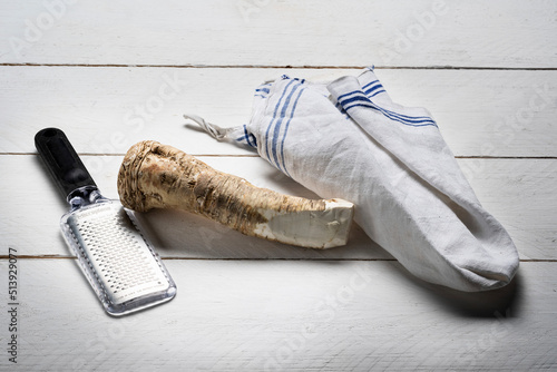 Horseradish root and grater on white wooden background photo