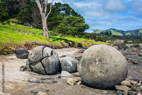 Large round boulders on a sandy beach by the hill. Koutu boulders, Hokianga Harbour, New Zealand photo