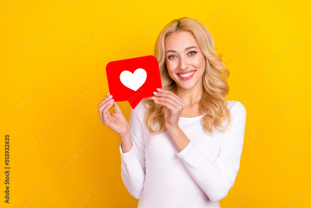 Photo of sweet millennial blond lady hold like wear trend cloth isolated on yellow color background Photo of sweet millennial blond lady hold like wear trend cloth isolated on yellow color background