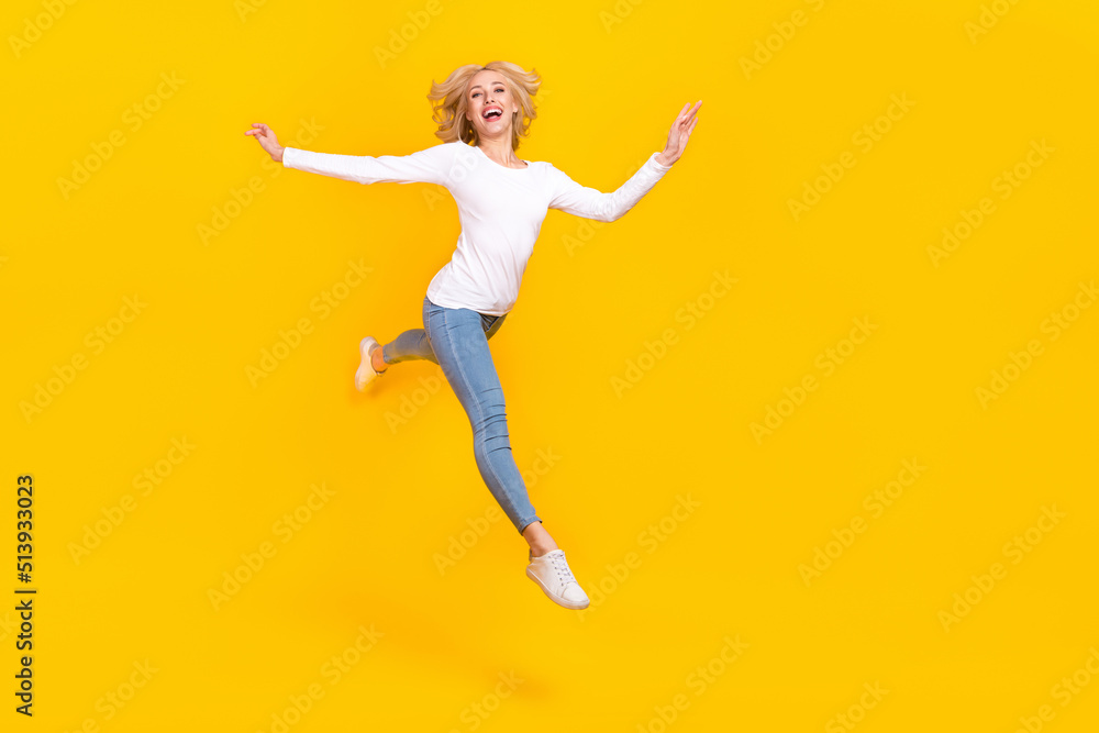 Full body photo of impressed young blond lady jump wear shirt jeans sneakers isolated on yellow background