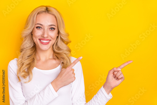 Photo of pretty funny young woman wear white shirt pointing fingers empty space isolated yellow color background