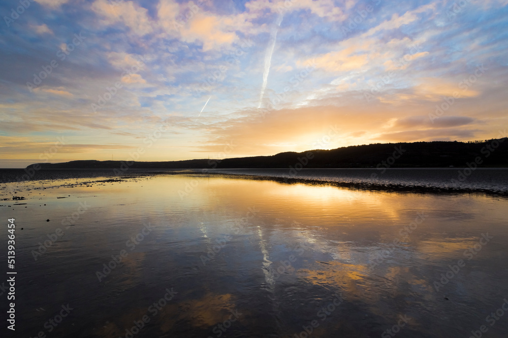 Stunning sunrise and sky reflection on the surface of Red Wharf Bay, Area of Outstanding Natural Beauty, Isle of Anglesey, North Wales Stunning sunrise and sky reflection on the surface of Red Wharf Bay, Area of Outstanding Natural Beauty, Isle of Anglesey, North Wales