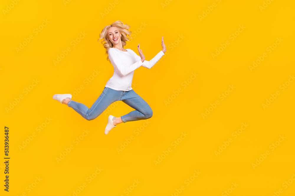 Full size photo of pretty millennial blond lady jump wear shirt jeans shoes isolated on yellow background