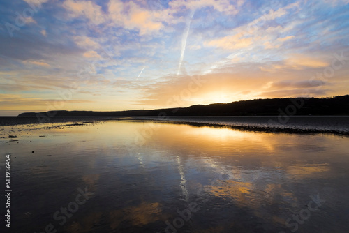 Stunning sunrise and sky reflection on the surface of Red Wharf Bay, Area of Outstanding Natural Beauty, Isle of Anglesey, North Wales