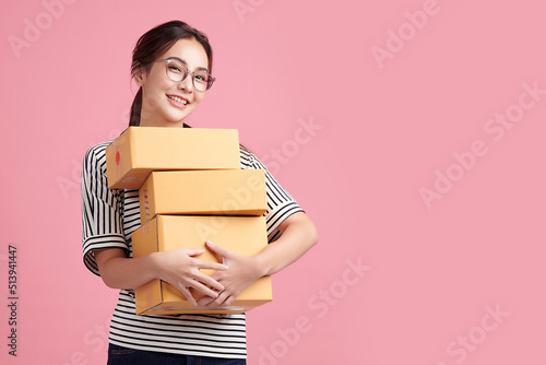 Beautiful Young Asian woman holding parcel box isolated on pink background, Delivery courier and shipping service concept. © kitthanes