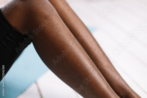 Bare legs of afro american woman closeup  blurred background free copy space. Black person lying with bent legs. Hairy and unshaven legs  new normal  beauty and fashion  body positive. 