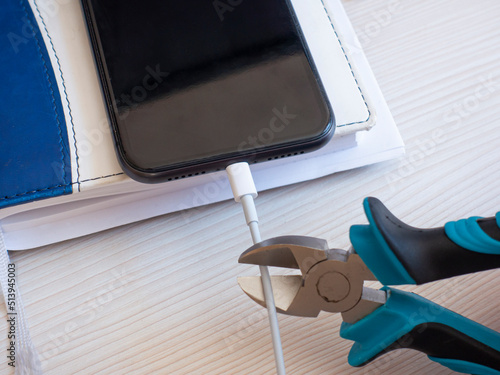 Wire cutters want to bite the smartphone charging wire, deprive the phone of recharging, hard disconnection of the cable photo