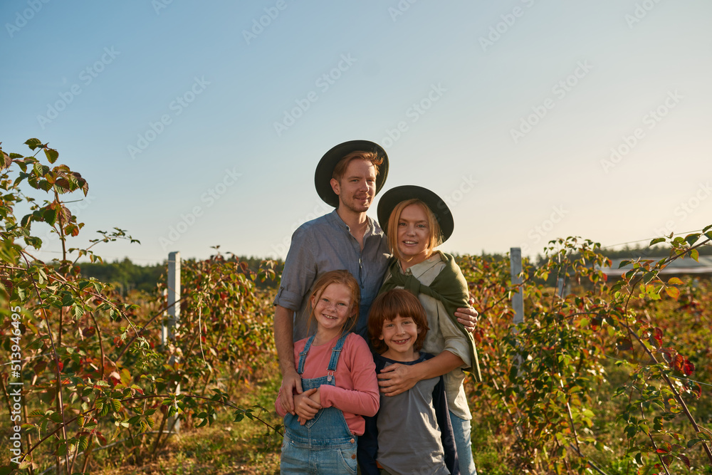 Farm family hug and look at camera in garden Farm family hug and look at camera in garden