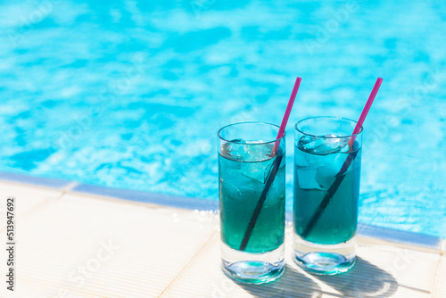 Chilled soft drinks, blue cocktails with ice near the swimming pool in sunny day.