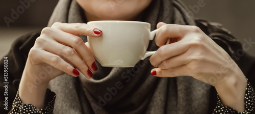Close up woman hands with red manicure holding coffee cup, vintage toned