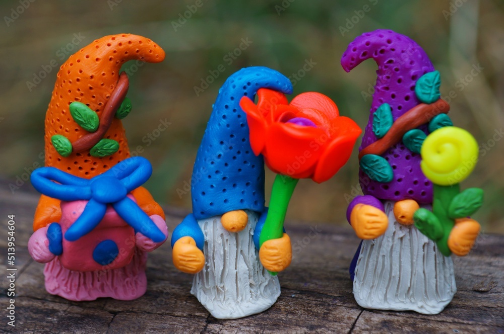 Toy gnomes with a flower and a gift. Fabulous scenery. Plasticine figurines. A festive event.