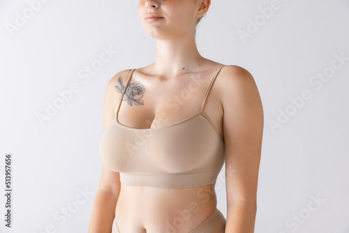 Cropped image of female body, breast in comfortable cotton underwear isolated over grey studio background. Mammoplasty