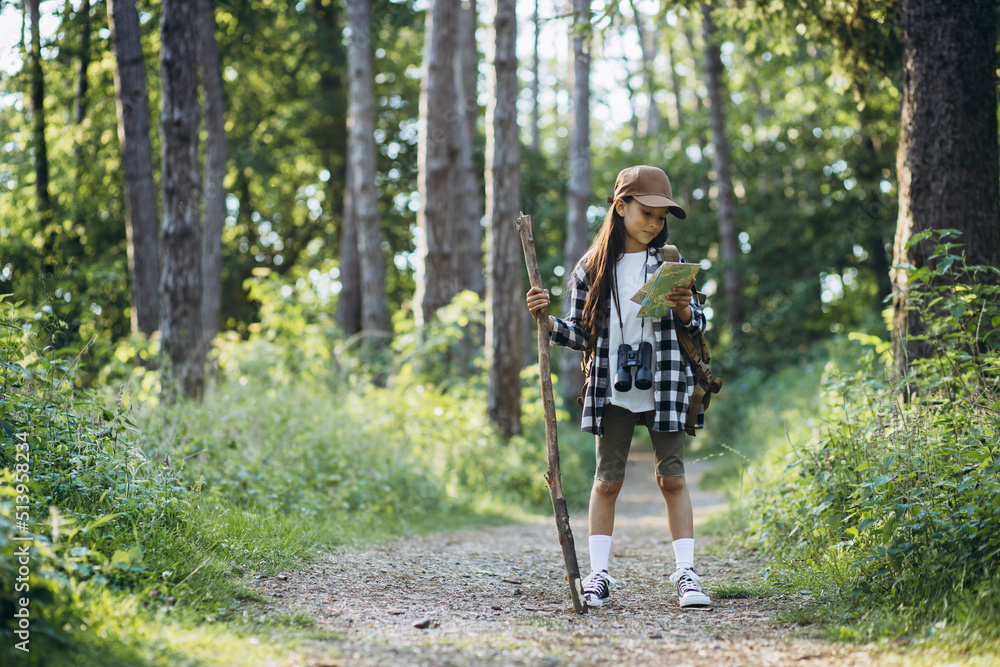 Girl looking at the map while walking in the forest Girl looking at the map while walking in the forest